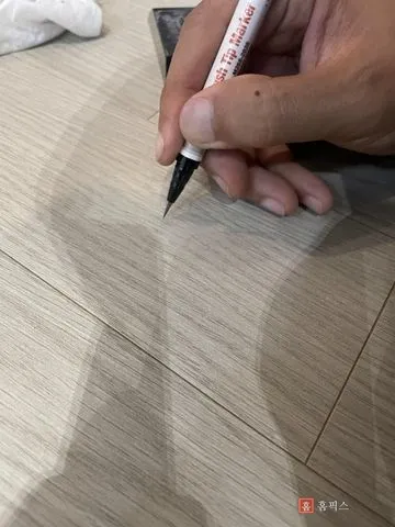 펜으로 메운 자리에 마루 나뭇결 무늬를 그려 넣는 모습