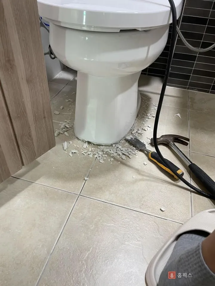 변기 발 주변 줄눈을 끌과 해머로 떼어낸 자리와 부스러기