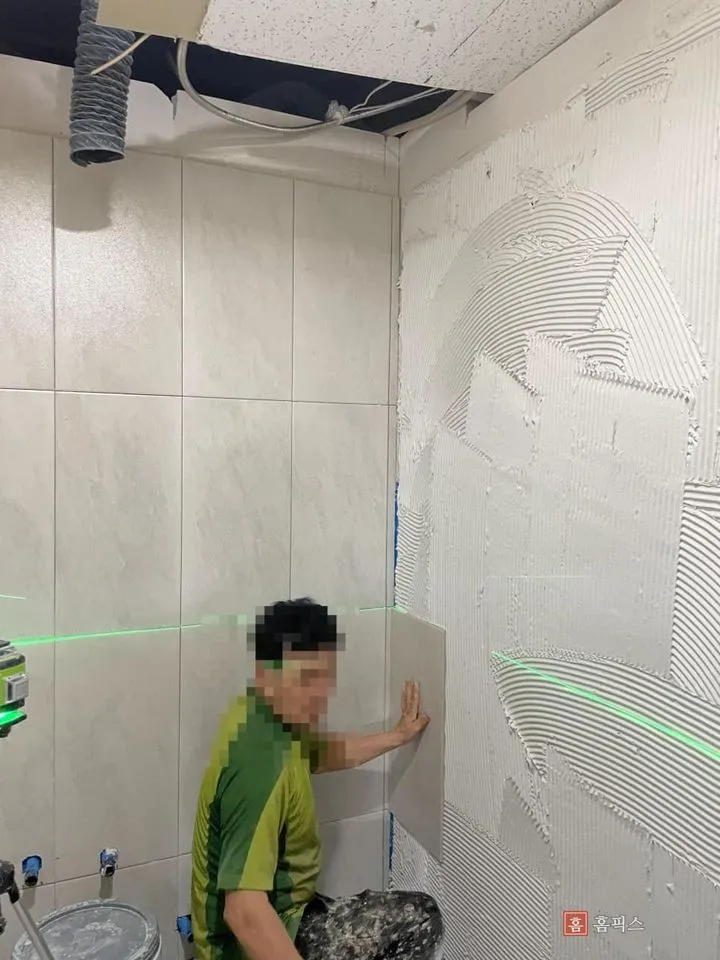 레이저 수평기 선에 맞춰 벽타일을 붙이는 작업 모습