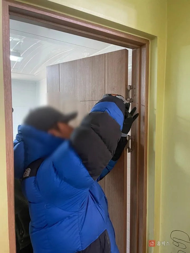 경첩을 풀어 기존 문짝을 떼어 내는 작업자