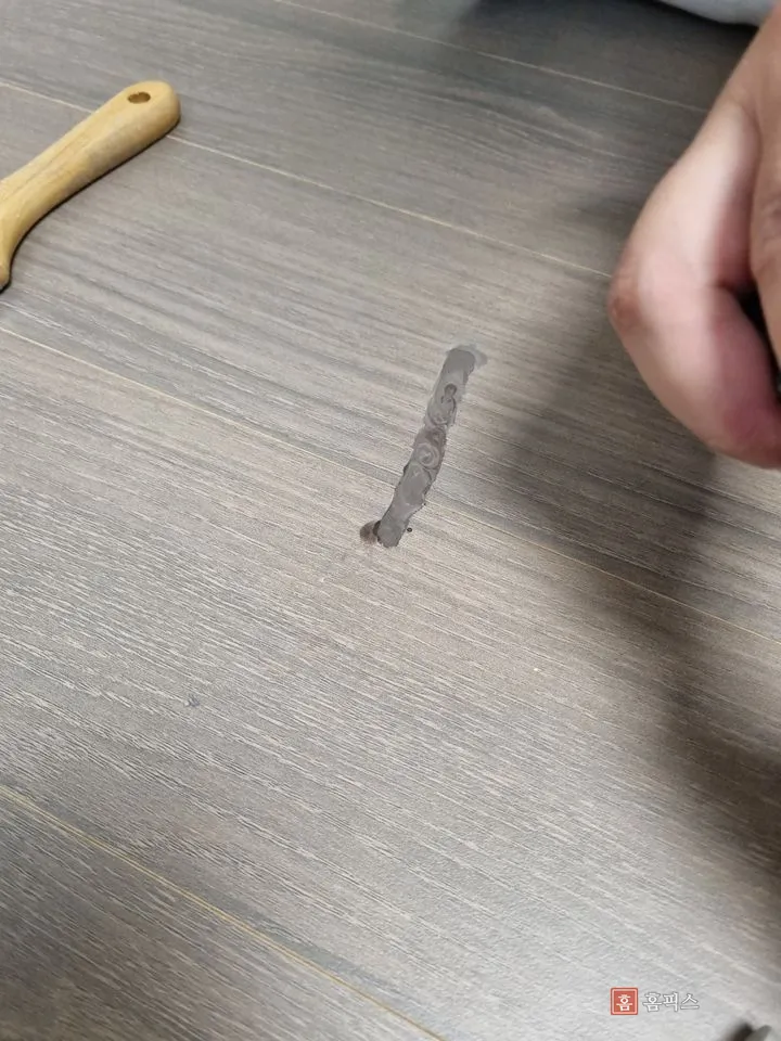 마루 상처에 전용 퍼티를 채워 넣은 모습과 스크래퍼