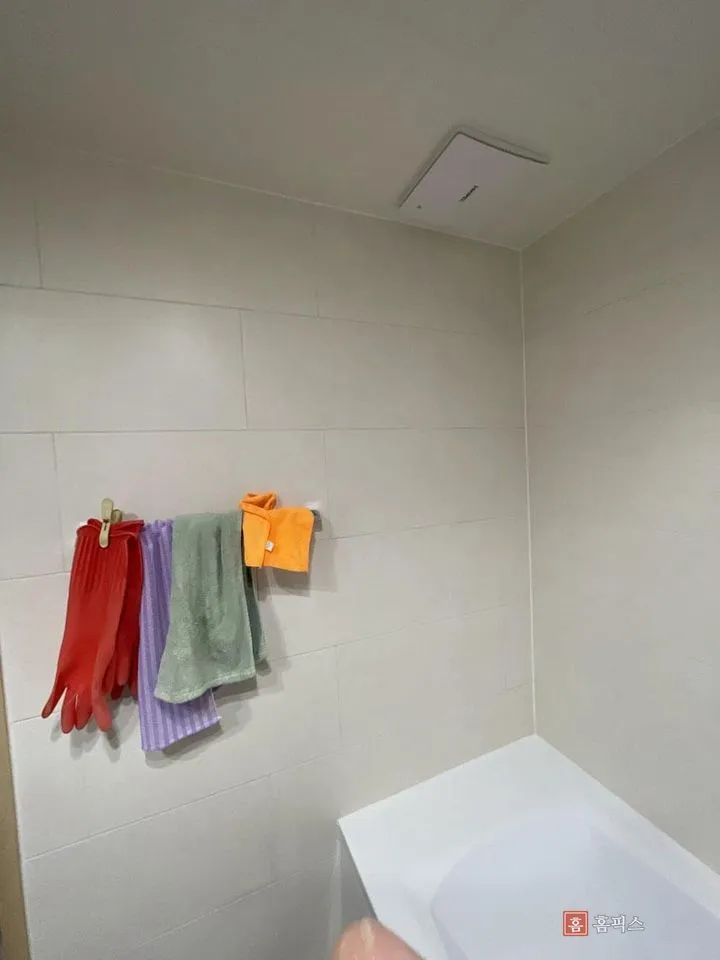 1단 수건걸이에 수건과 고무장갑이 걸려 있는 욕실 벽