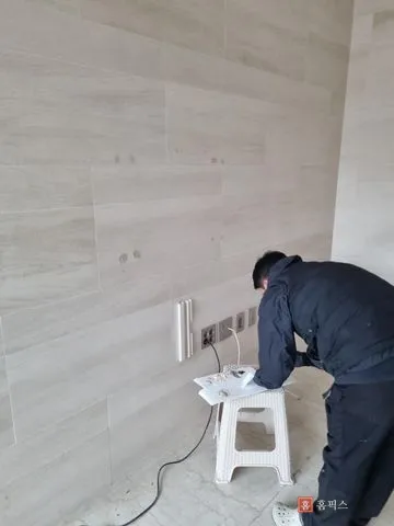 벽 앞에서 종이 위에 퍼티를 올려 조색 중인 작업자
