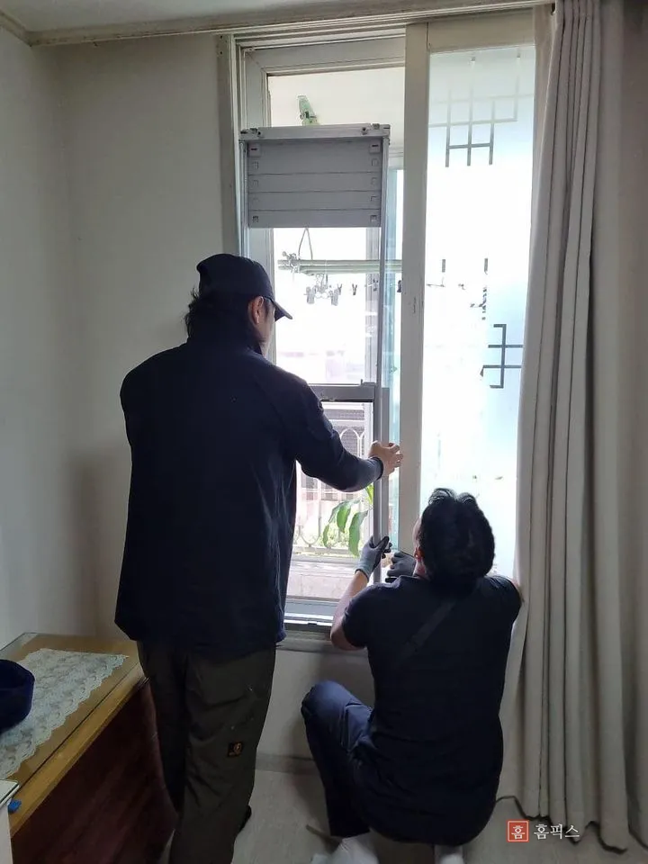 안방 창틀에 거치대를 올리고 위치를 잡는 작업자 두 명