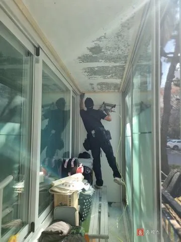 사다리 위에서 타카로 골조를 잡는 작업 장면